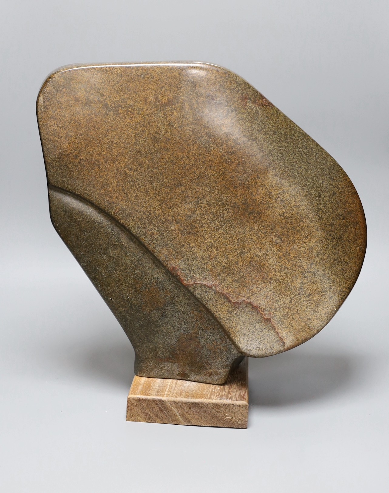 A Zimbabwean carved and polished stone abstract study of a head with a fist, 35cms.